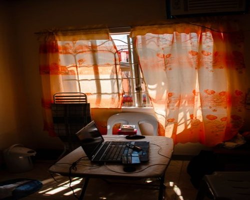 Person working on a laptop at a small desk setup in a Chilean apartment, with natural light coming through the window.